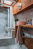 Low bathroom with marble tiles, toilet and wooden washbasin