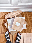 Stack of delivered cardboard parcels on a door mat to apartment entrance