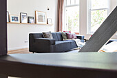 Grey sofa with throw pillows, wall of windows and picture shelf in the living room