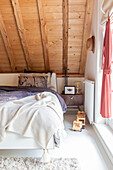 Attic bedroom with wooden beamed ceiling, bed and toy trolley