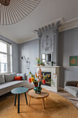 Living room with grey walls, stucco decoration and fireplace, and round wooden tables