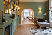 Living area with green wall color, bookshelf and arched opening to the living room