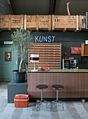 Retro-style sales counter with bar stools, neon lettering and wooden crates