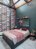 Bedroom with floral wallpaper and green walls, double bed and shelf with decorative elements