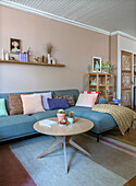 Living room with blue sofa, colorful cushions and wooden table on carpet