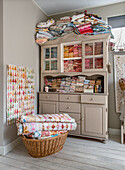 Vintage kitchen cupboard with lots of colorful fabrics, wicker basket with patchwork quilts