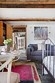 Room with stone floor, grey sofa, wooden beamed ceiling and colorful carpet