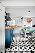 Kitchen with blue and white color palette, patterned tiled floor and copper pendant light