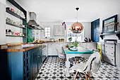 Modern kitchen with mint green dining table, copper pendant lamp and patterned tiled floor