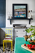 Kitchen with oil painting, yellow chair, mint green table and geometric floor pattern