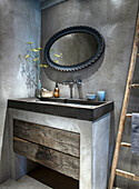 Concrete and reclaimed wood washbasin in modern bathroom with oval mirror