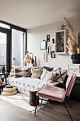 Cosy living room corner with velvet chair and textiles in natural tones