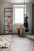 Modern bathroom corner with wooden towel ladder and stool