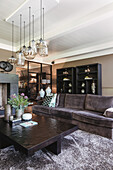 Living room with brown velvet sofa, hanging glass pendant lights and display cabinets