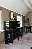 Black piano and decorative objects in a room with a sloping ceiling