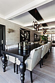 Long dining table with light-coloured upholstered chairs and tinted glass pendant lights in the dining room