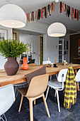 Dining table with modern chairs and white pendant lights and garland on the ceiling