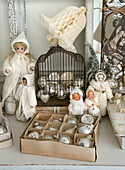 Silver Christmas ornaments in a cage and in a box, surrounded by cotton dolls, Christmas bell made of crepe paper