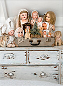 Doll collection on old chest of drawers in shabby style