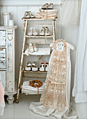 Ladder with old, white children's shoes, girl's dress and bridal veil