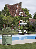 Poolbereich mit Liegestühlen und Sonnenschirm vor ländlichem Anwesen