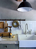 Kitchen utensils on concrete countertop and farmhouse sink, black lamp above sink