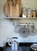 Shelf with wooden boards and storage jars, including vintage utensils above the oven