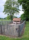 Hühnerstall umgeben von Holzzaun auf ländlichem Grundstück
