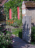Stone path leads to a rustic garden with flowering plants