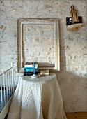 Side table with empty picture frame in front of natural stone wall