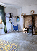 Blue chair and framed butterfly collection in corner of room next to brick wall with wood-burning stove