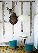 Eclectic corner with deer head, modern lamp and colorful stools