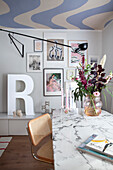 Dining area with marble table top, painted ceiling and colorful pictures on the wall