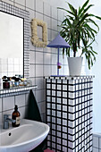 Bathroom with white tiled paneling and mosaic mirror