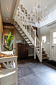 Staircase with white staircase, chandelier and dark flooring