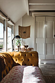 Bright study with ochre-coloured Chesterfield sofa