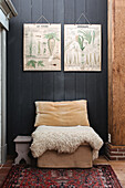 Armchair with lambskin and botanical picture panels on a dark wall