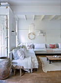 Bright living room with white corner sofa, wooden ceiling and rustic decorative elements