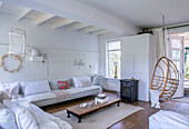 Bright living room with hanging chair, white sofa and wooden table