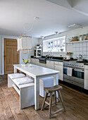 White country kitchen with wooden floor, dining table and bench