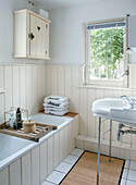 Bright bathroom with wood paneling, bathtub and white sink