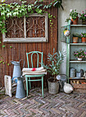 Garden corner with plant shelf, watering cans and vintage chair