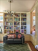 Reading corner with black leather sofa and built-in bookshelf in the living room