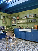 Kitchen with blue wooden cupboards, green wall and patterned floor tiles