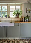 Kitchen with grey-green cupboards and ornamental tiles