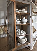 Vintage display cabinet with white country-style porcelain service