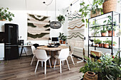 Hell eingerichtete Küche mit Esstisch, Makramee-Wandbehängen und Zimmerpflanzen