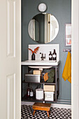 Small bathroom with round mirror and patterned floor tiles