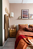 Bedroom with patterned bed linen and wall decor in earthy tones