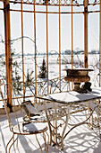 Verschneiter, antiker Gartentisch mit Stuhl und Bank im Wintergarten